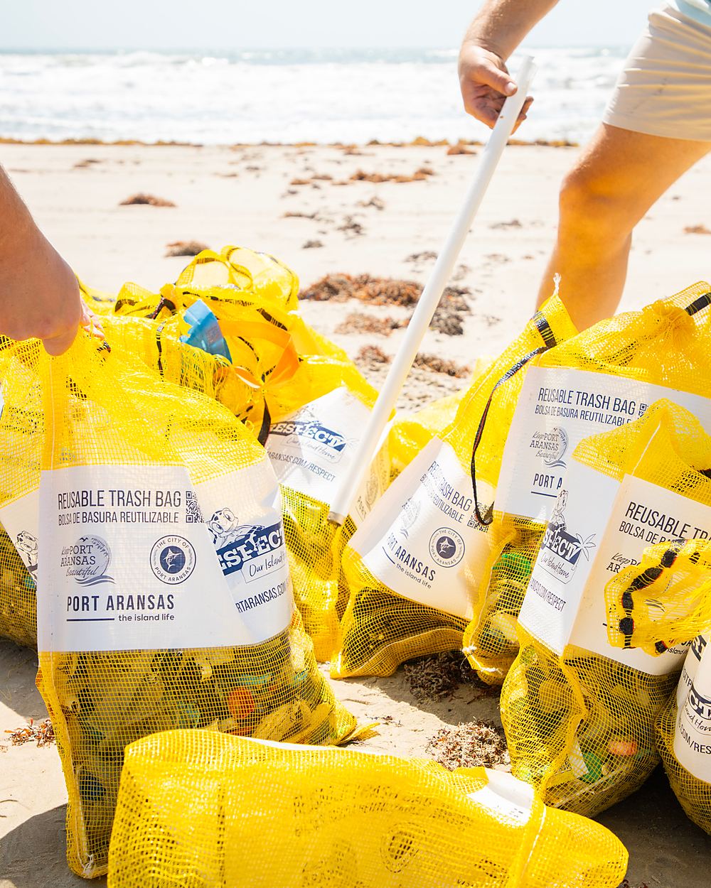Collection bags filled and stacked at the end of a shoreline cleanup